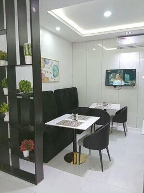 A modern waiting area with a reception desk, seating, and a mounted television. - DELIZ HOMES AND HOTEL (Lekki)