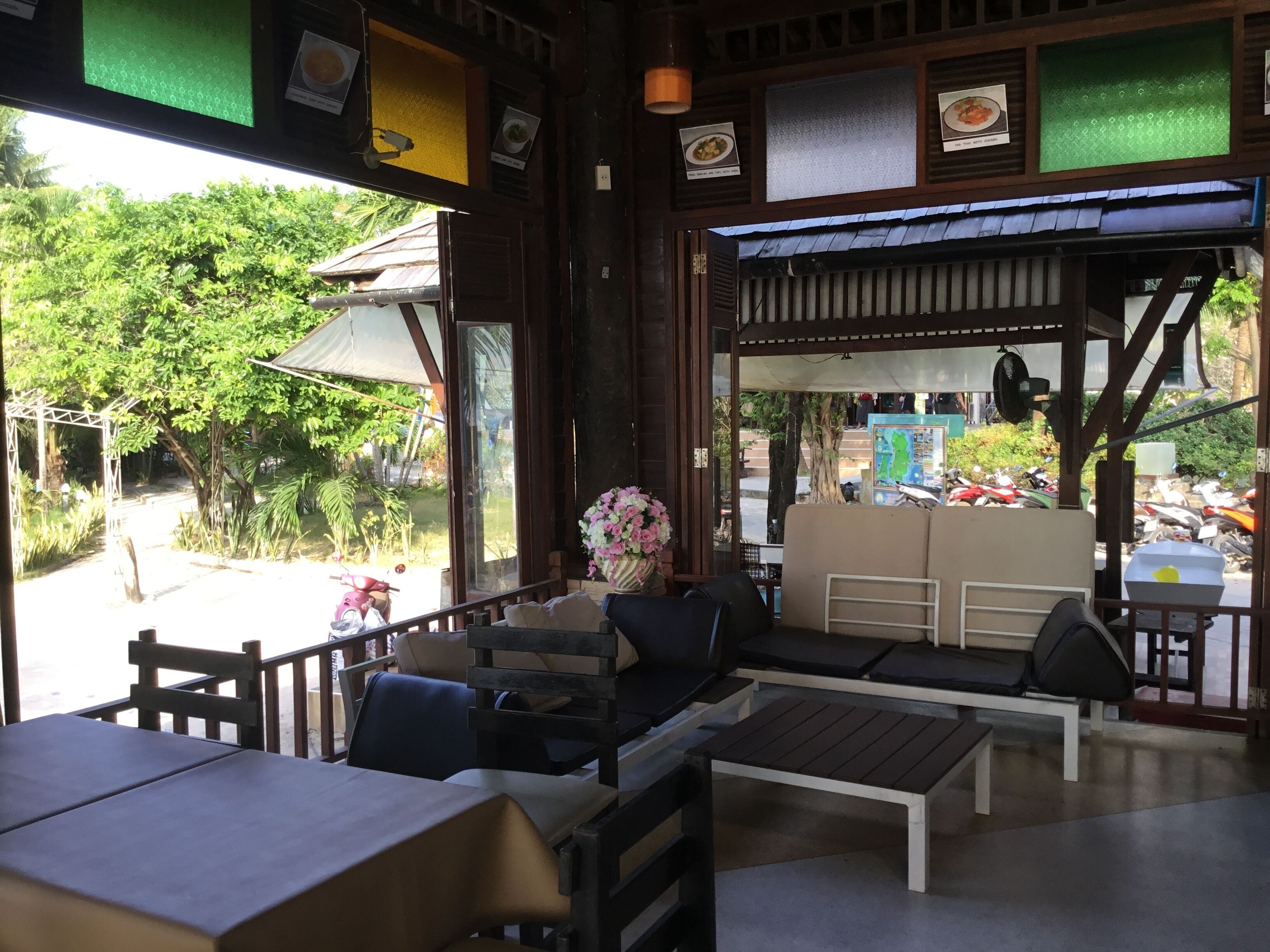 A restaurant with outdoor seating, a covered area, and a view of the surrounding greenery.
