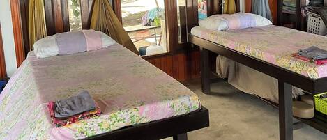 Una habitación con dos camas, paredes de madera y ventiladores de techo.