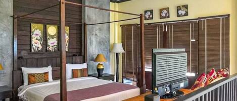 A bedroom with a four-poster bed, a desk with a computer, and a TV.
