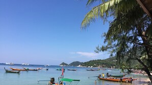 A beach with boats docked and people on the shore. - Seashell Resort Koh Tao (Koh Tao)