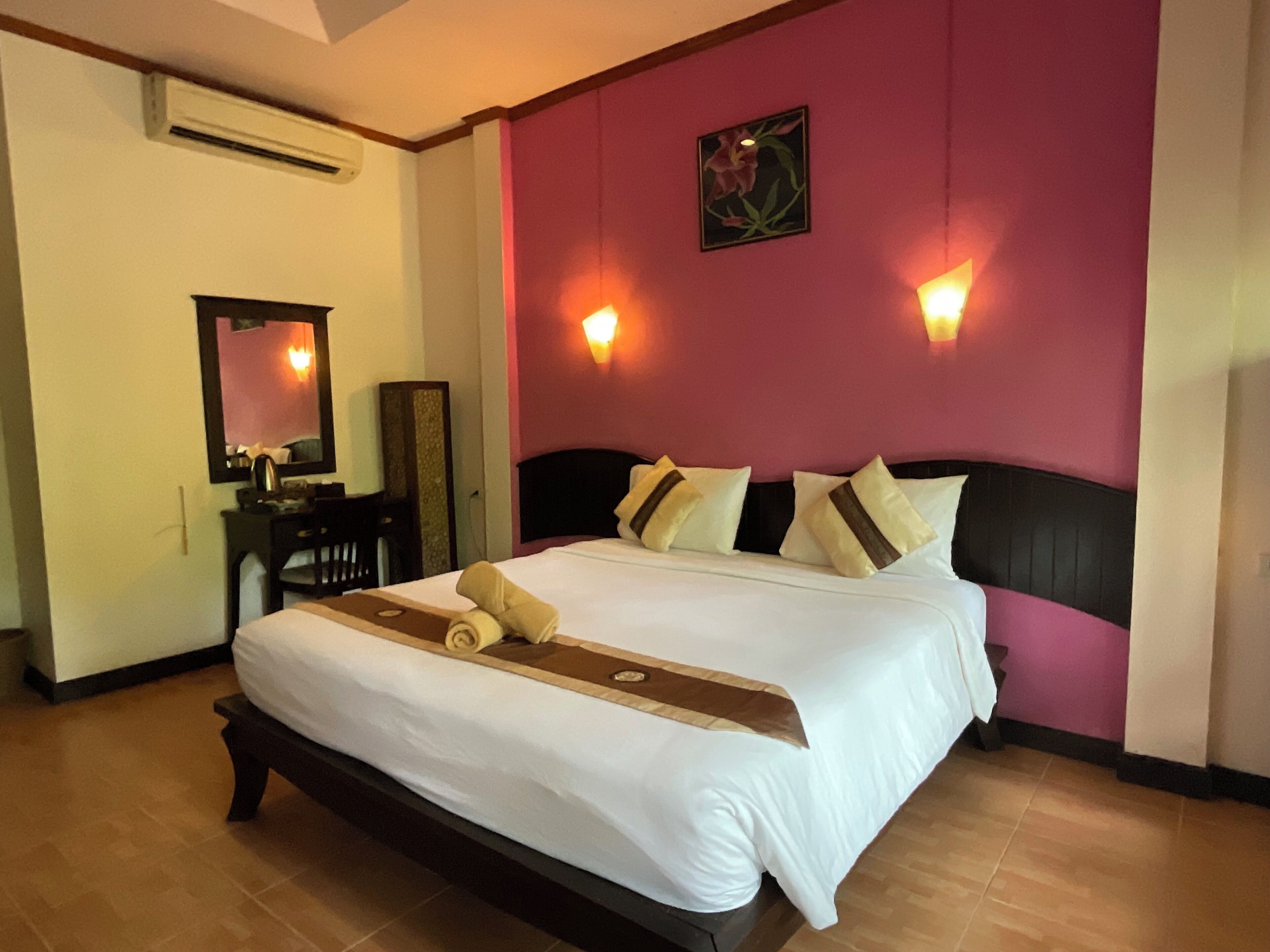 Habitación de hotel con una cama grande, un escritorio, una silla, un espejo y aire acondicionado de pared.