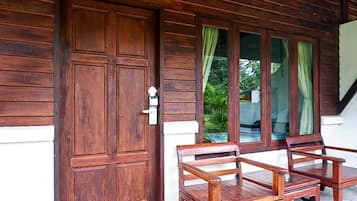 Una puerta de madera con una placa de número, un banco y una ventana con cortinas.