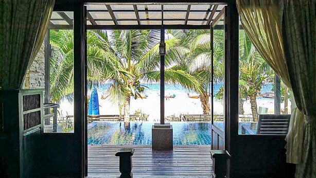 A room with a view of a swimming pool, palm trees, and a beach. - Seashell Resort Koh Tao (Koh Tao)