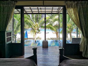 A room with a view of a swimming pool, palm trees, and a beach. - Seashell Resort Koh Tao (Koh Tao)