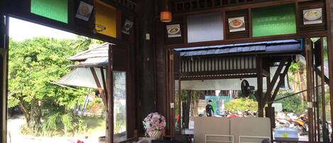 An indoor dining area with wooden furniture, a view of the outdoors, and a menu board.