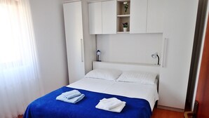 A neatly made bed with a blue bedspread and two folded white towels, a white wardrobe with a mirror, and a small shelf with decorative items. - Comfortable accommodation for 4 people in the center of Starigrad (Starigrad)