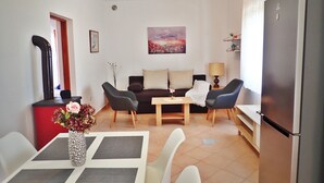 A compact living space with a dining area, a sofa, a table with chairs, a refrigerator, and a decorative vase with flowers. - Comfortable accommodation for 4 people in the center of Starigrad (Starigrad)