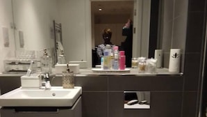 Een moderne badkamer met toilet, wastafel en spiegel.