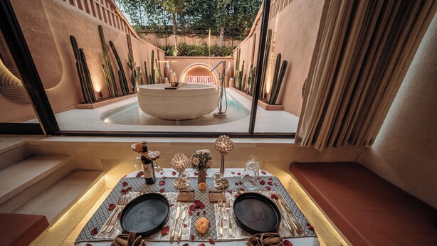 Un bagno di lusso con una vasca da bagno ampia, uno specchio e un angolo relax con petali di rosa.