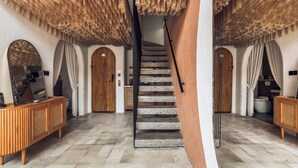 Una scala con un design unico del soffitto, una consolle in legno e un muro a specchio.