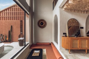 Une salle de bain moderne avec une baignoire, un meuble-lavabo en bois, un miroir et une fenêtre donnant sur des cactus.