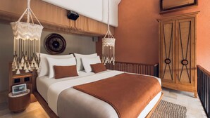 A bedroom with a large bed, bedside tables, a wall-mounted air conditioner, and a decorative wall hanging.