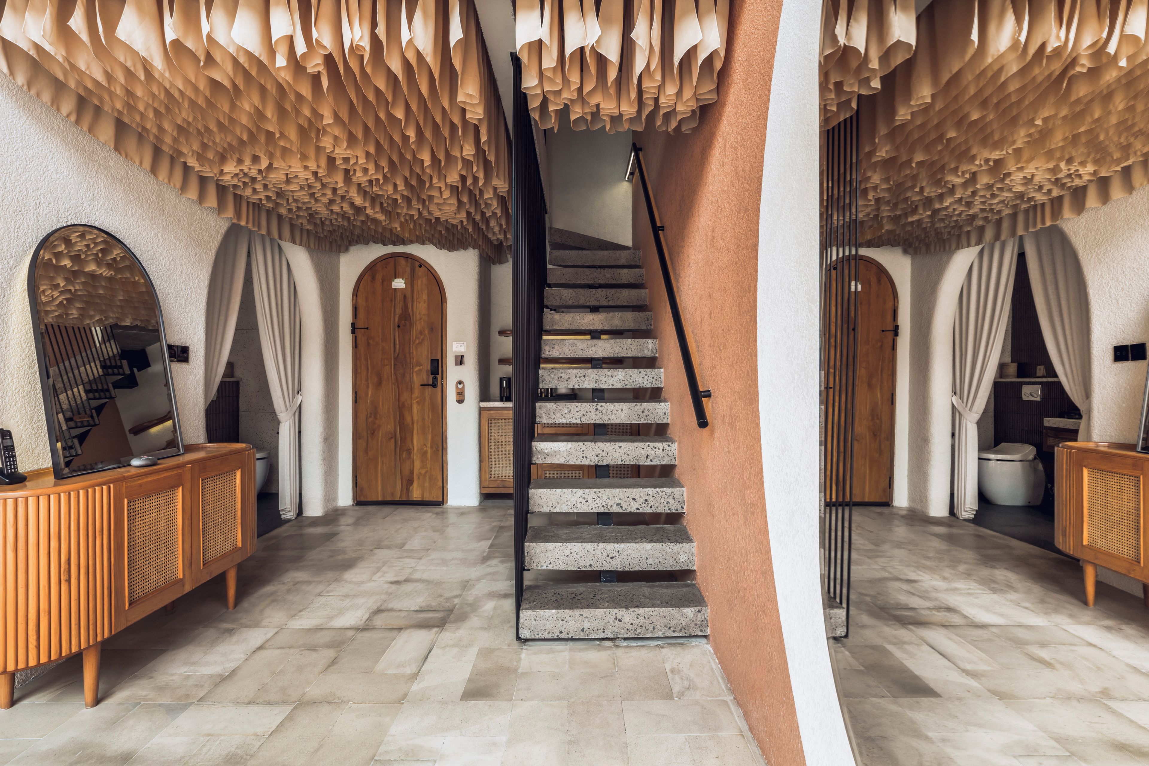 Una escalera de diseño moderno que lleva a un rellano con una puerta de madera y un espejo.