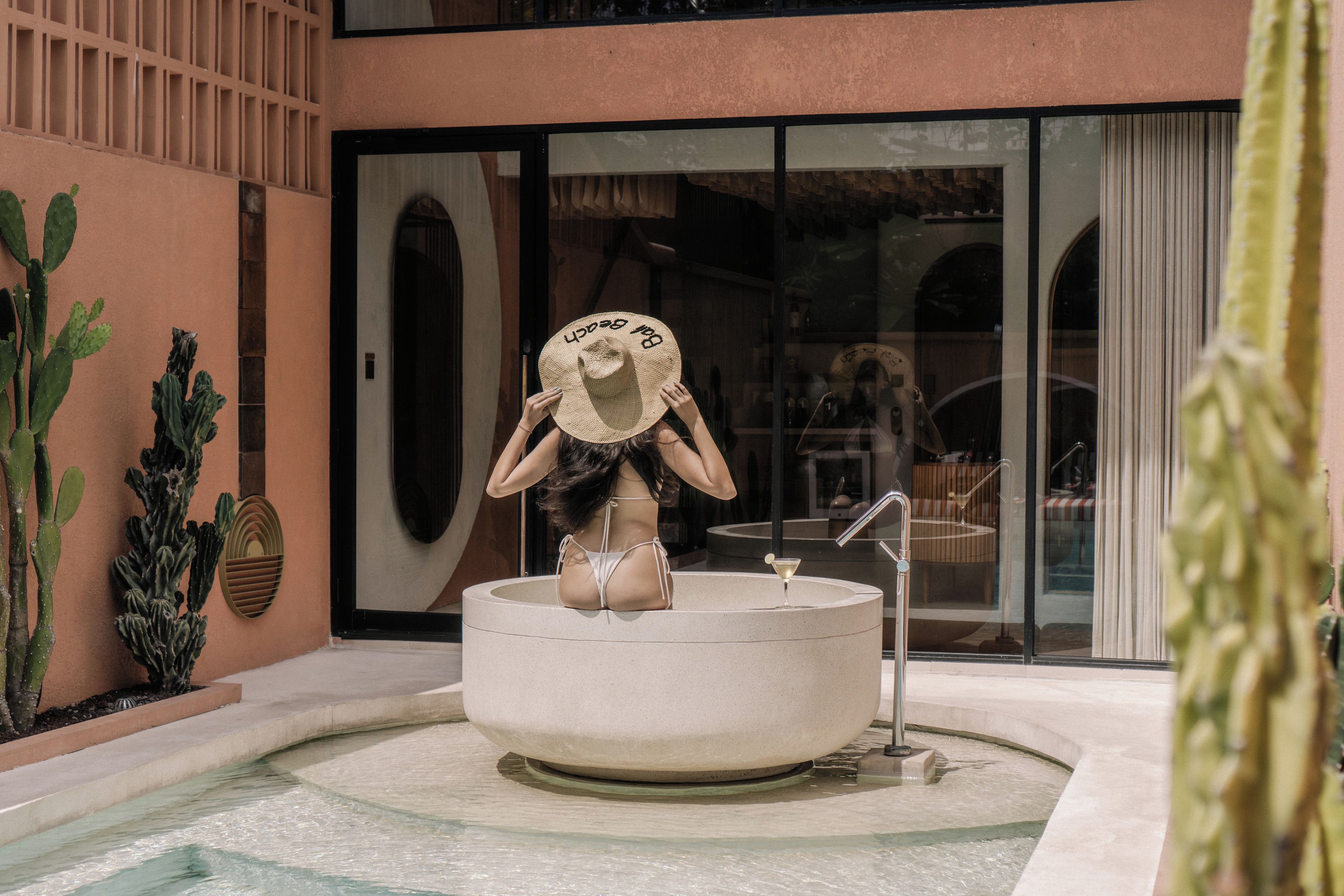 A spa area with a hot tub, a large window, and cacti.