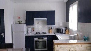 Eine moderne Küche mit dunklen Schränken, einer Arbeitsplatte aus Stein und einem Essbereich mit Tisch und Stühlen.