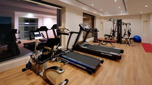 Un gimnasio con cintas de correr, elíptica y máquina de pesas.