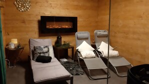 Una habitación acogedora con chimenea, dos sillones reclinables, una mesita con una estatua de Buda y un espejo.