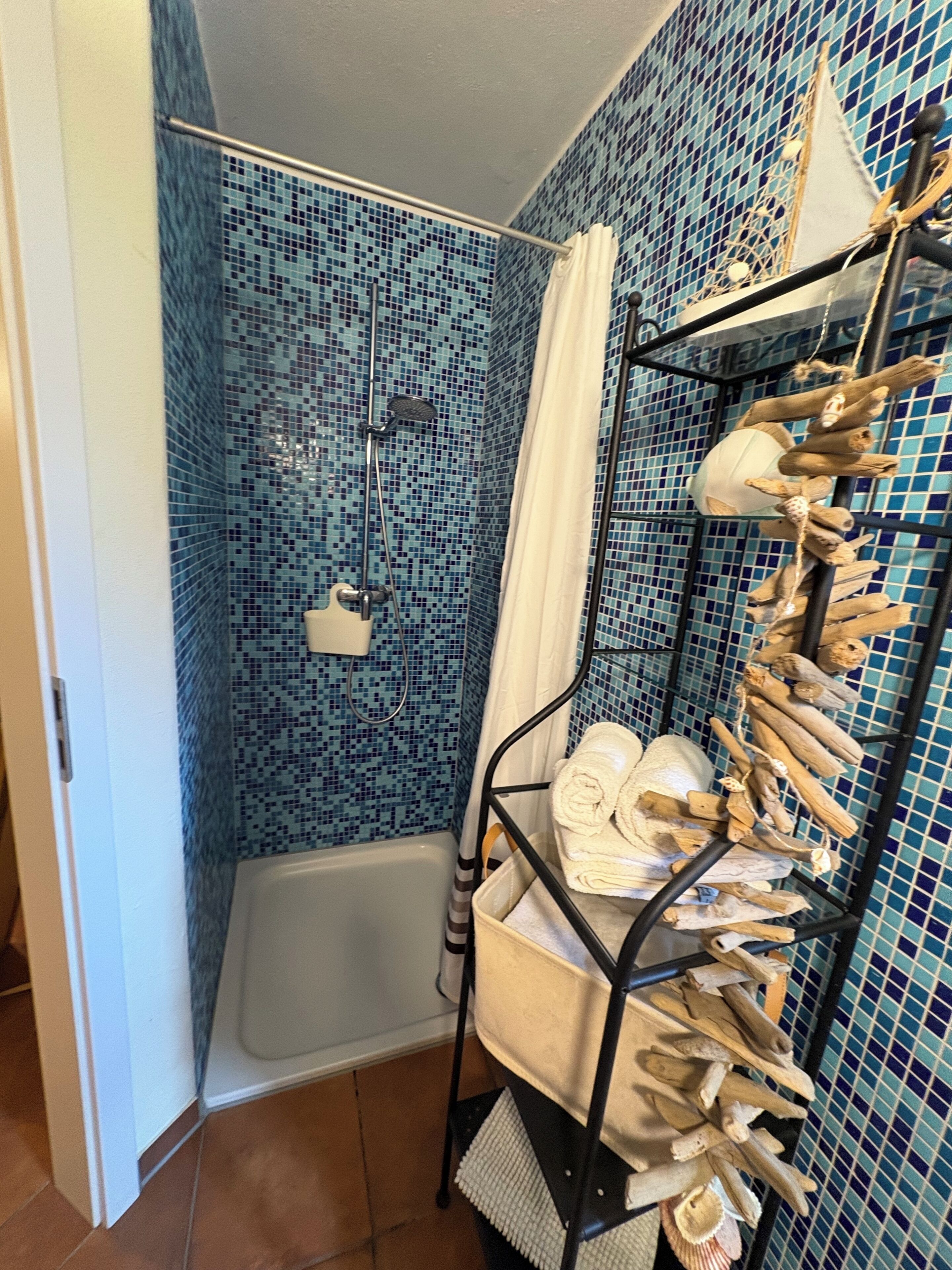 A bathroom with a shower, a bathtub, and a shelf with towels and toiletries.