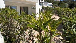 A modern building with a white facade, a stone pathway, and lush greenery. - Villa with swimming pool and directly by the sea on the Rte des Sanguinaires (Ajaccio)