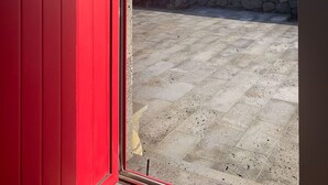 A red door leading to a balcony with a view of the ocean and a stone wall. - Stylish 1 Bedroom Stone House On Ocean Front - São Jorge, Azores (Bela Lua) (Calheta)