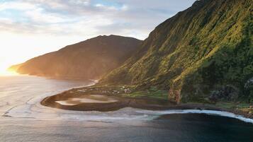 A coastal landscape with a mountain, a beach, and a small settlement.