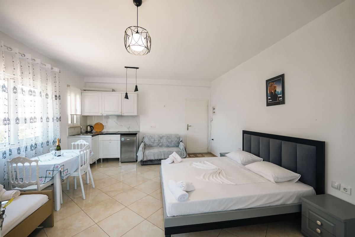 A hotel room with a bed, bedside table, and a small kitchenette.