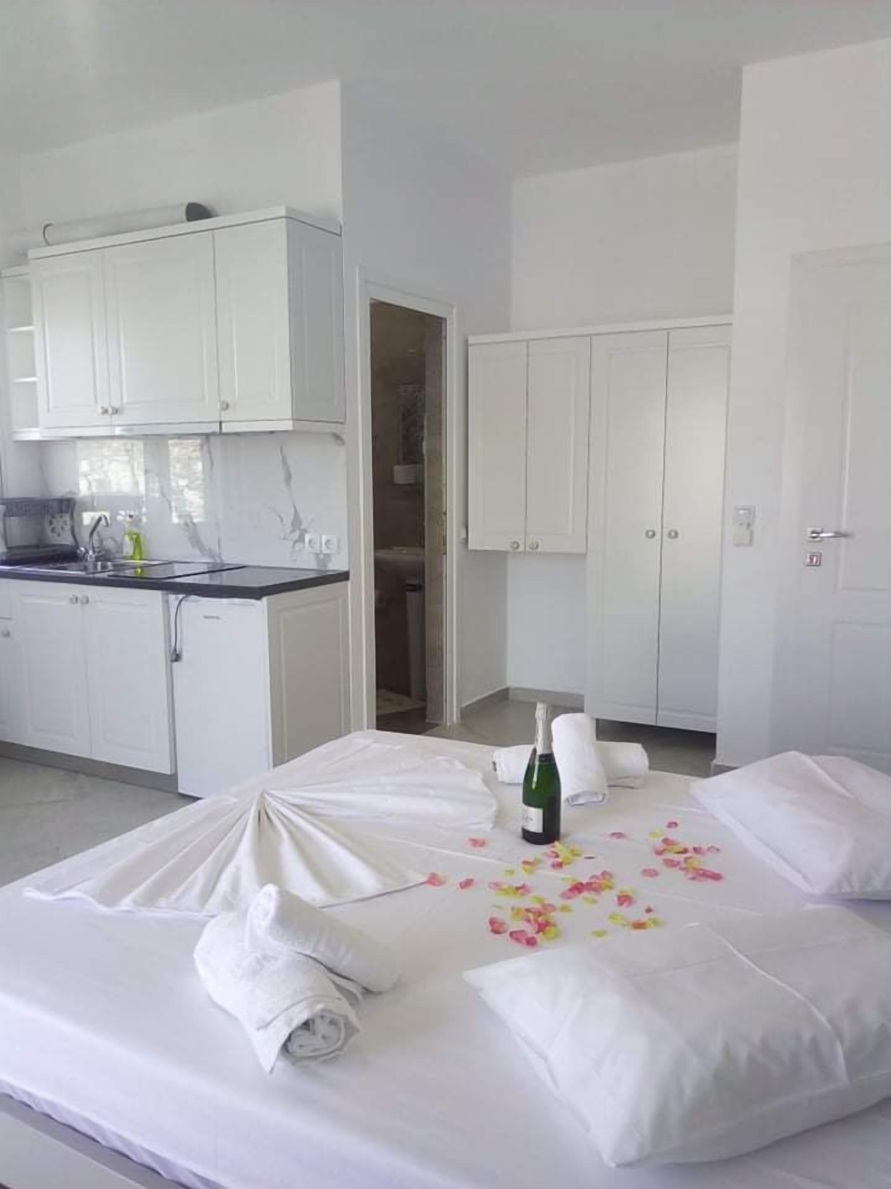 A hotel room with a bed, a bottle of champagne, and a towel.