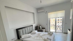 Un dormitorio moderno con cama, mesitas de noche, escritorio y vistas al exterior.