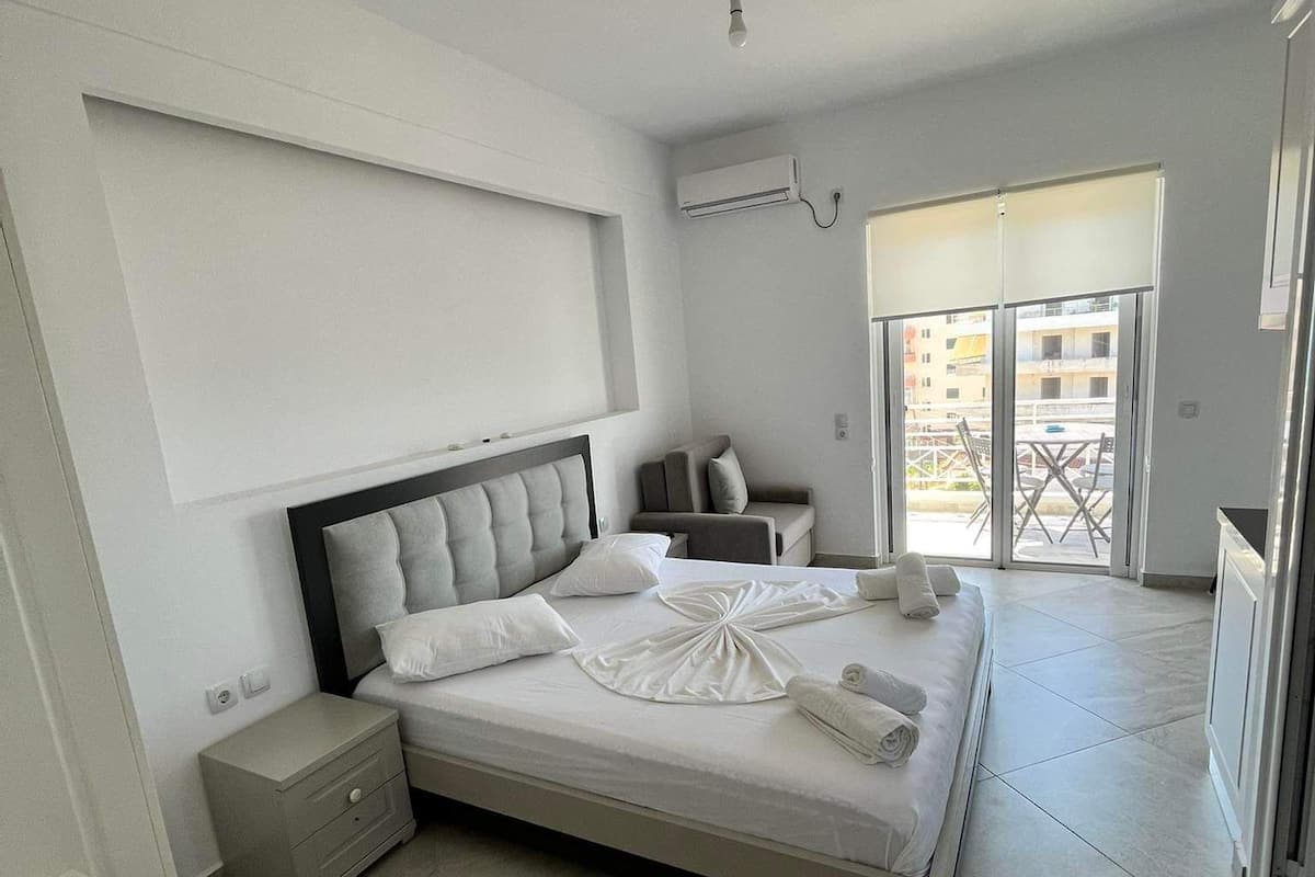 A modern bedroom with a bed, bedside tables, a desk, and a view of the outside.