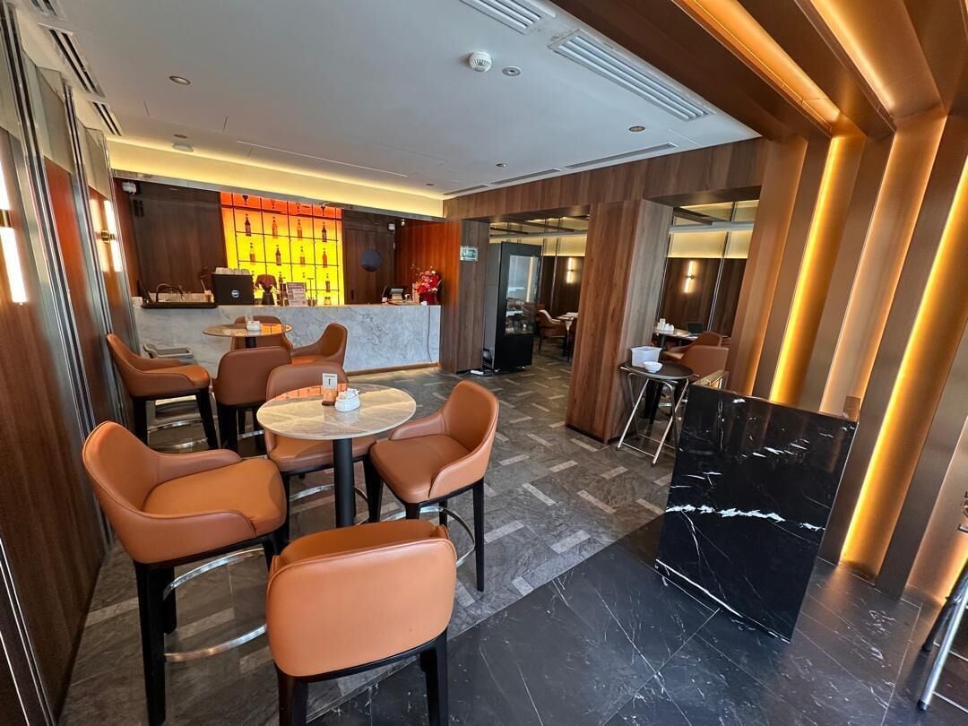 Un moderno vestíbulo de hotel con asientos de cuero, un mostrador de recepción de mármol y una zona de bar.