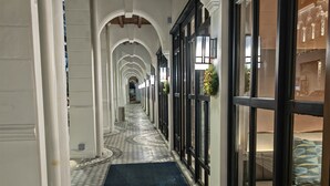 A hallway with patterned floor tiles, white columns, and large windows with black frames. - Citadines Connect Georgetown Penang (George Town)