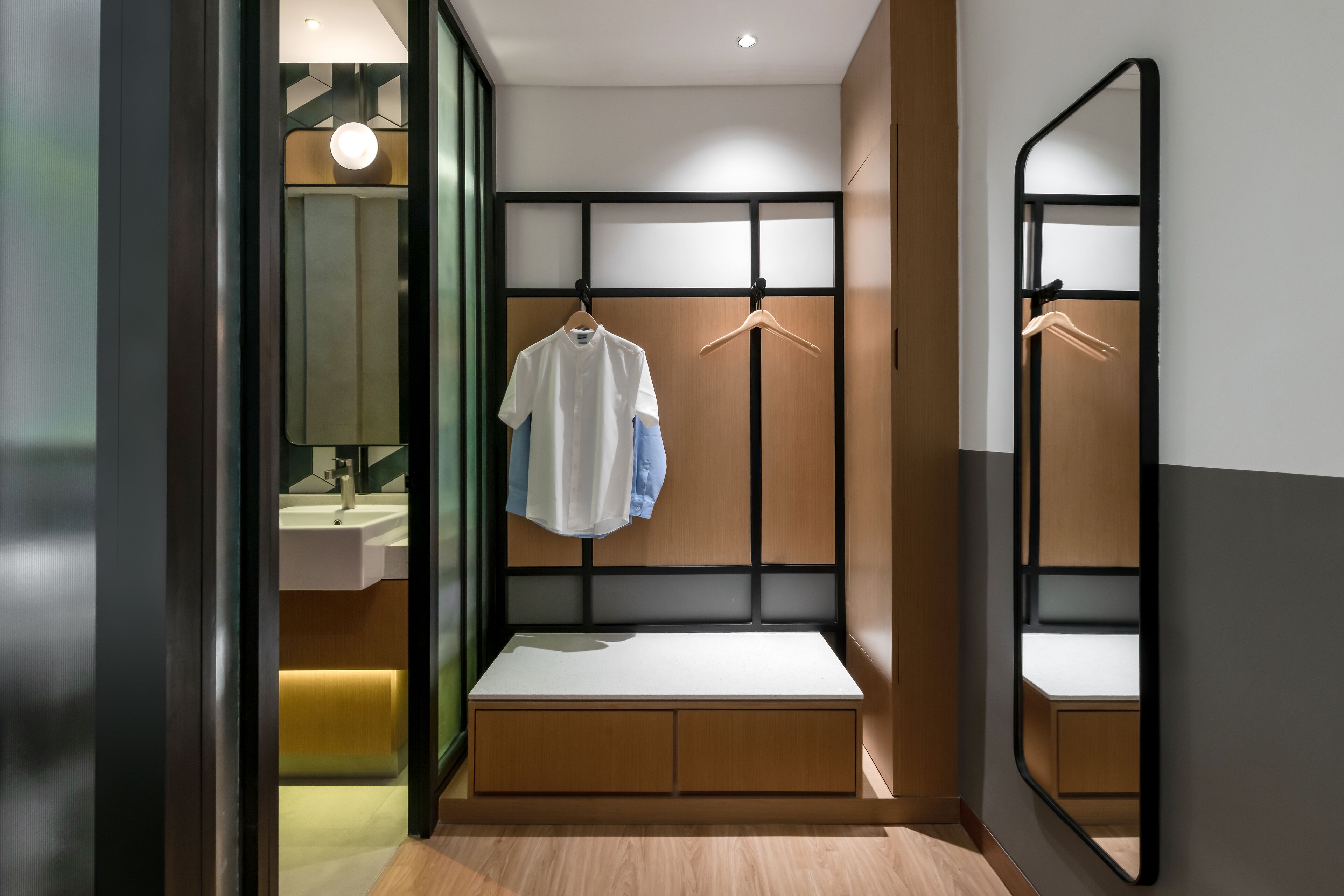 Egy modern fürőszoba, amelyben van egy pad, egy tükör és egy függesztett ruhaszárító.