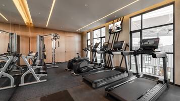A modern gym with treadmills, elliptical machines, and weightlifting equipment.