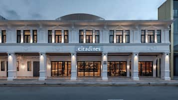 A hotel with a classical facade, multiple entry points, and illuminated signage.