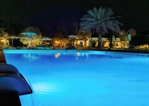 Alberca al aire libre, sombrillas en la alberca y camastros