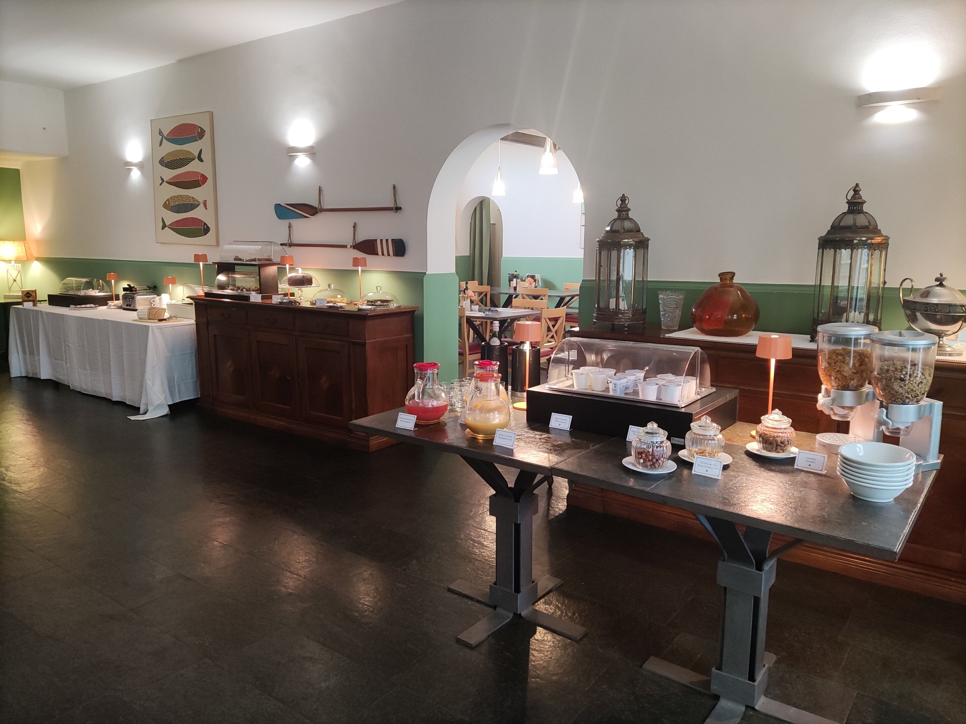 Ein reichhaltiges Buffet mit verschiedenen Speisen und Getränken, eine Holztresen und eine Wand mit dekorativen Fischdarstellungen.