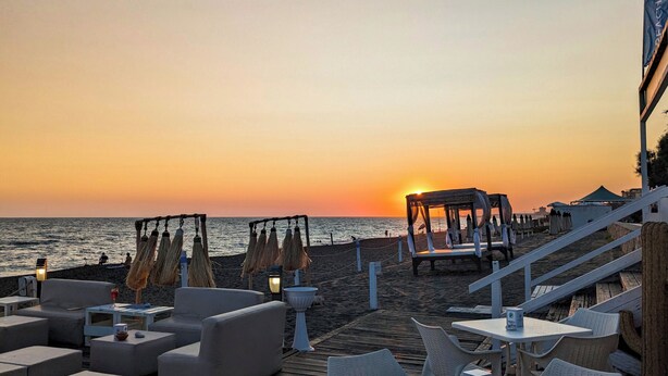A beachside terrace with outdoor seating, a wooden deck, and a sunset view. - Riva di Palo Resort (Ladispoli)