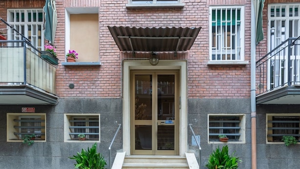 A building entrance with a double door, steps, potted plants, and a metal awning. - GuestHost - San Donato Fiera Apartment (Bologna)
