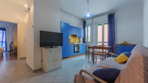 A living room with a sofa, TV, and dining area. - GuestHost - San Donato Fiera Apartment (Bologna)