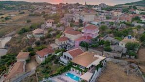 A coastal village with traditional architecture, a prominent church, and a swimming pool area.