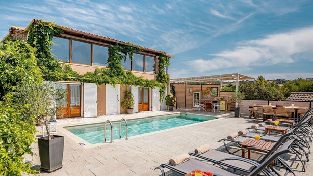 Un área junto a la piscina con sillones de descanso y un bar.