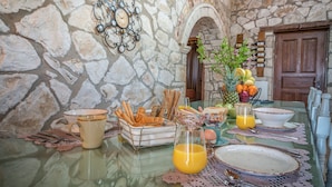 Una escena de desayuno con paredes de piedra, un reloj y un frutero.