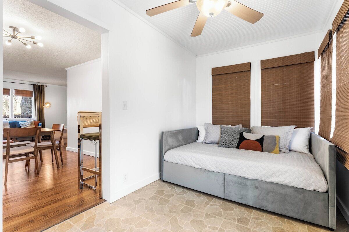 Quarto com cama, ventilador de teto e janela com persianas.