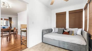 Quarto com cama, ventilador de teto e janela com persianas.