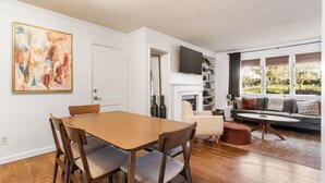 Ein modernes Wohnzimmer mit Essbereich, Kamin und großem Fenster mit Blick.