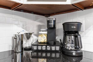 Una cuina amb una cafetera, un bullidor, un molinet de cafè i una forquilla per a cafè a la barra.