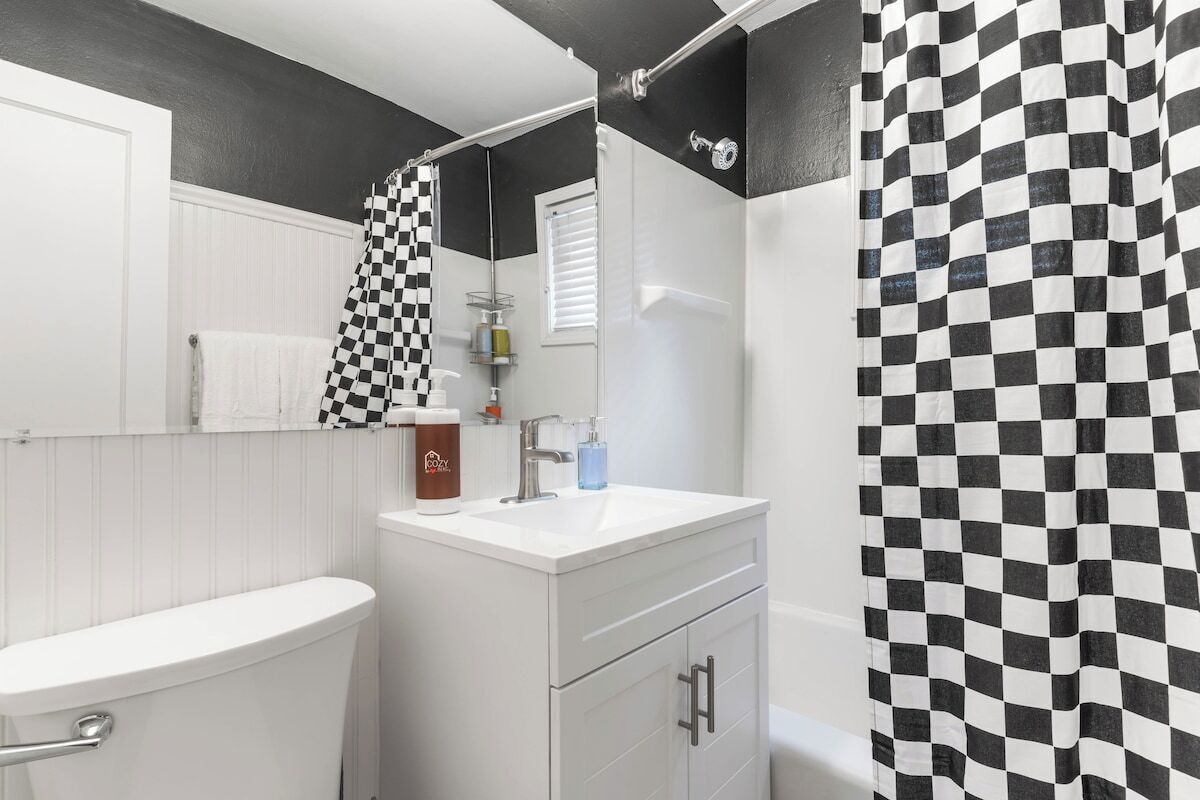 A bathroom with a white sink, a mirror, a towel rack, and a shower curtain with a checkered pattern.