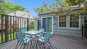 Eine Terrasse mit einem Tisch und Stühlen mit Glasplatte, umgeben von einem Holzboden und einem Metallzaun.