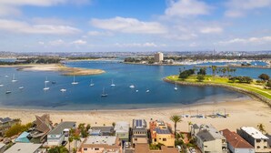 Un pueblo costero con un puerto deportivo, playa de arena y edificios residenciales.